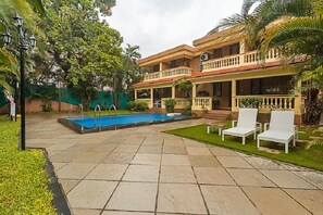 A two-story building with a swimming pool, outdoor seating, and a well-maintained garden. - De Mandarin Beach Resort Suites & Villas Goa (Candolim)
