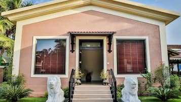 A two-story house with a central entrance, a small porch, and two stone lion statues.