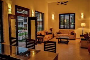 A living room with a sofa, coffee table, and dining table. - De Mandarin Beach Resort Suites & Villas Goa (Candolim)