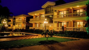A multi-story hotel with balconies, a swimming pool, and a well-maintained garden. - De Mandarin Beach Resort Suites & Villas Goa (Candolim)