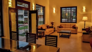 A living room with a sofa, coffee table, and dining table. - De Mandarin Beach Resort Suites & Villas Goa (Candolim)