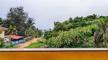 Una vista de un paisaje verde y exuberante con un camino que lleva a un edificio de techo rojo.