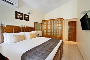 Un dormitorio con una cama de madera, un armario, un televisor y un aire acondicionado instalado en la pared.