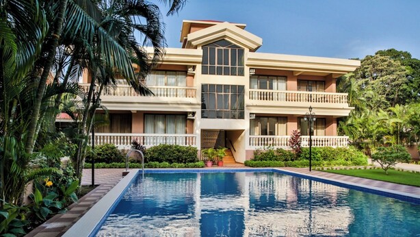 A hotel with a swimming pool, a two-story building, and a well-maintained garden. - De Mandarin Beach Resort Suites & Villas Goa (Candolim)