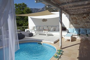 A poolside area with a seating arrangement, a pool, and a view of the mountains. - Mare Monte Boutique Hotel (Thasos)