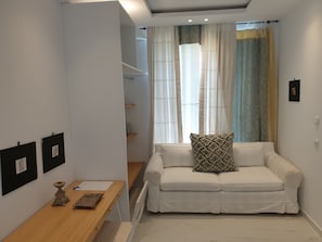 A modern living room with a white sofa, a wooden table, and a staircase leading to a loft area. - Mare Monte Boutique Hotel (Thasos)