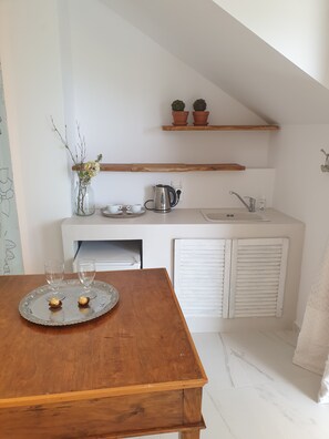 A compact kitchen with a wooden table, a kettle, and a tray with two glasses. - Mare Monte Boutique Hotel (Thasos)