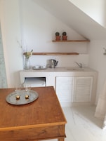 A compact kitchen with a wooden table, a kettle, and a tray with two glasses.
