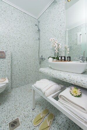 Een badkamer met een douche, wastafel en toilet, met een patroon op de wand en vloer, en een spiegel boven de wastafel.