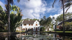 A hotel with a large building, a pond with lily pads, and palm trees.