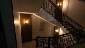 A staircase with a wrought iron railing and wall-mounted lights. - Skyline Hotel & Suite (Tabuk)