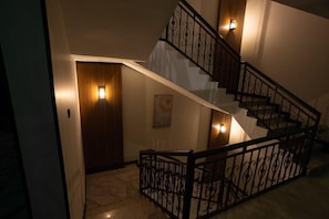 A staircase with a wrought iron railing and wall-mounted lights. - Skyline Hotel & Suite (Tabuk)