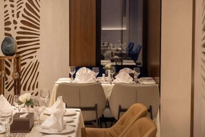 A dining area with tables set for two, a vase, and a clock on a side table. - Skyline Hotel & Suite (Tabuk)