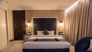 A hotel room with a large bed, bedside tables, a headboard, and curtains. - Skyline Hotel & Suite (Tabuk)