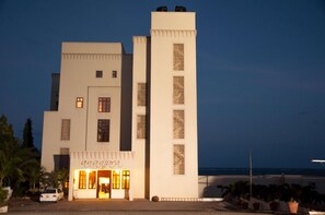 A modern building with a prominent vertical tower, a ground-level entrance with a sign, and a view of the sea in the background. - Sun Africa Beach Resort (Mombasa)