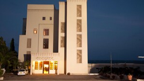 A modern building with a prominent vertical tower, a ground-level entrance with a sign, and a view of the sea in the background. - Sun Africa Beach Resort (Mombasa)