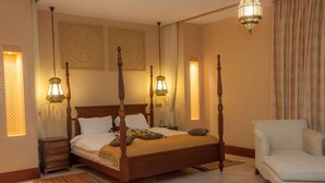 A four-poster bed with a wooden frame, a bedside table, a chair, and two wall-mounted lamps. - Sun Africa Beach Resort (Mombasa)