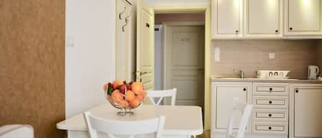 A dining area with a table and chairs, a fruit bowl, and a kitchen with cabinets and a sink.