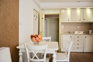 A dining area with a table and chairs, a fruit bowl, and a kitchen with cabinets and a sink. - Golden Rainbow (Nessebar)