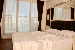 A hotel room with a large bed, a mirror, and sheer curtains. - Golden Rainbow (Nessebar)