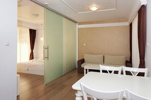 A room with a bed, a sofa, a dining table, and a sliding door. - Golden Rainbow (Nessebar)