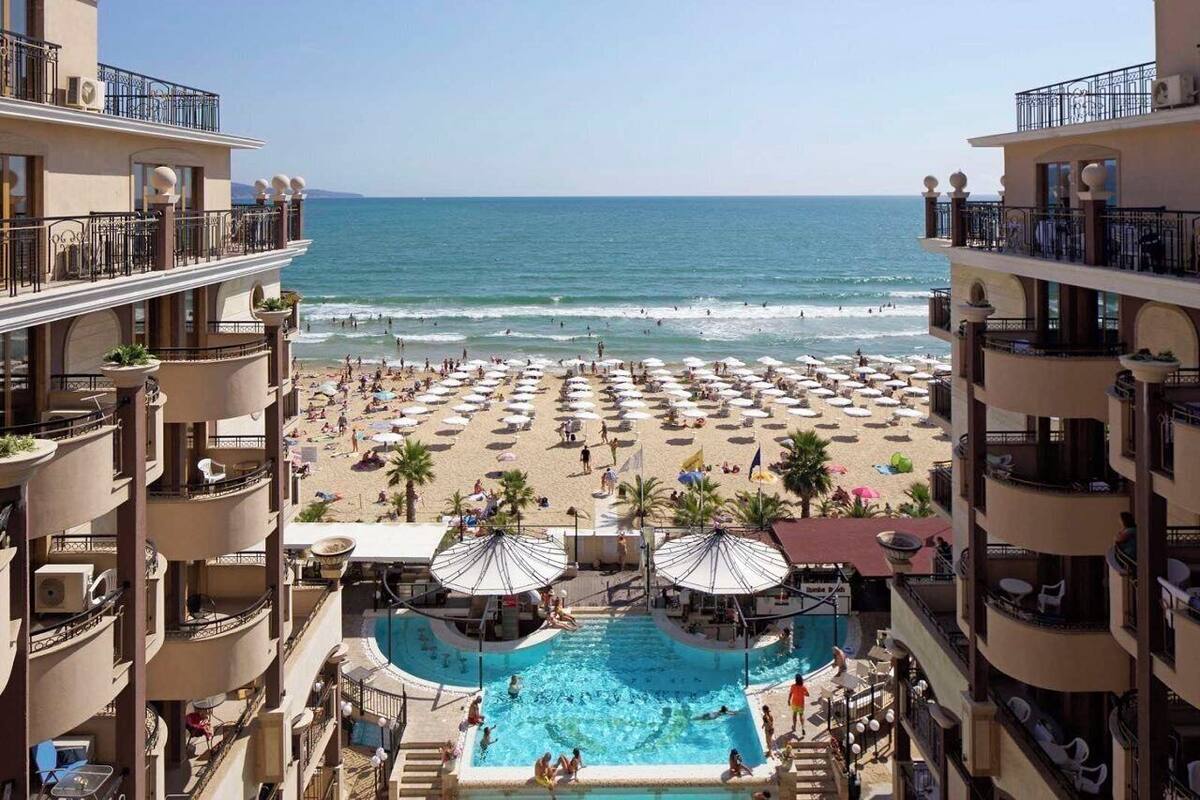 A hotel with a pool, beach, and ocean view.