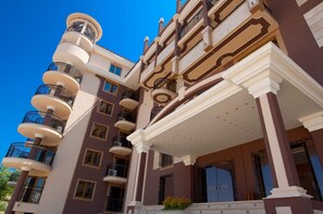A multi-story building with balconies, a grand entrance, and a clear sky. - Golden Rainbow (Nessebar)