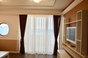 A hotel room with a large window, a television on a built-in shelf, and a round mirror on the wall. - Golden Rainbow (Nessebar)