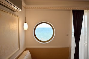 Een kamer met een rond raam, een wandairconditioner en een lamp.