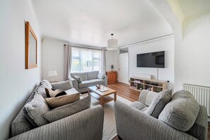Ein modernes Wohnzimmer mit einer Sofagarnitur, einem Couchtisch, einem Fernseher und einer Heizung.