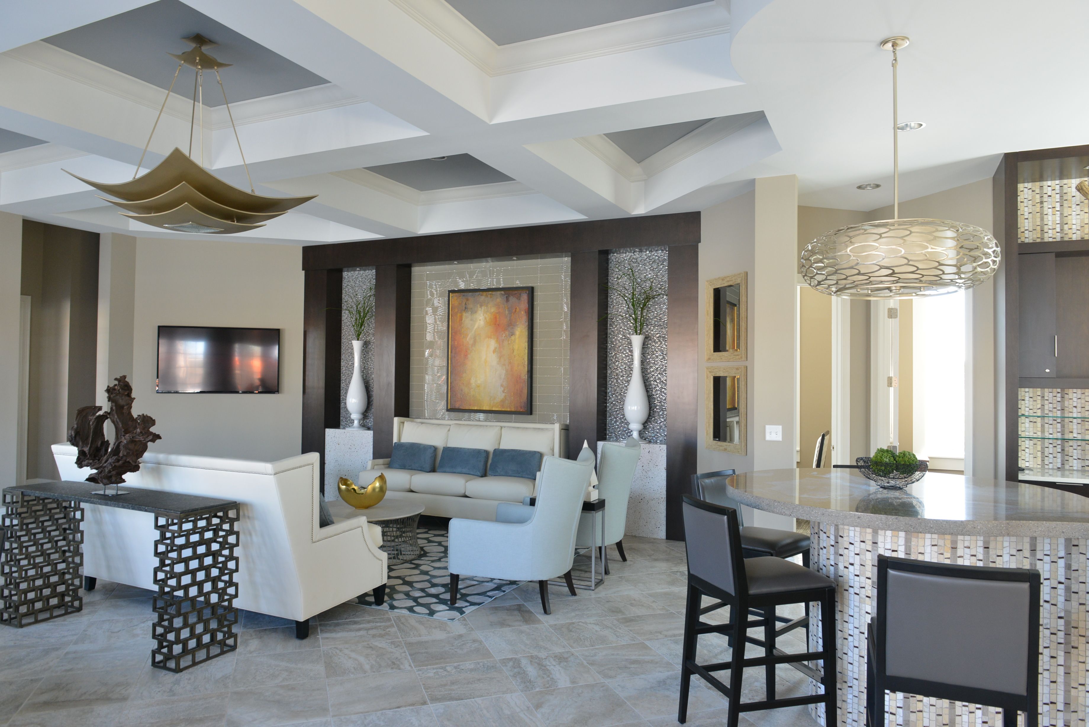 A modern living room with a sofa, chairs, a coffee table, and a dining area with bar stools.