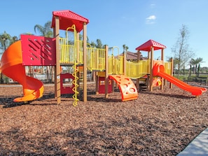 A playground with a spiral slide, climbing structures, and a small slide. - Solterra Resort Homes (Davenport)