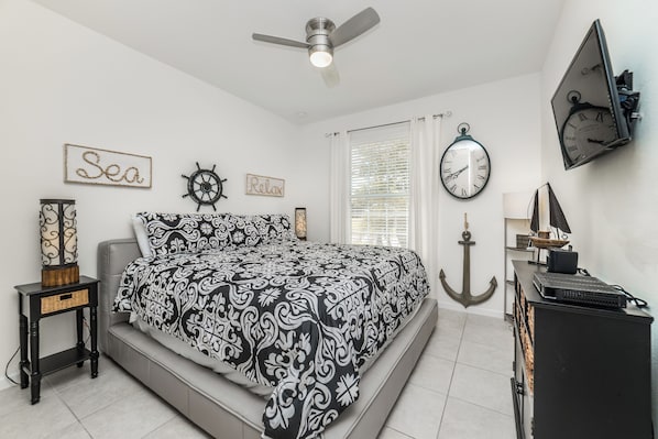 A bedroom with a bed, a ceiling fan, a wall clock, and nautical-themed decor. - Solterra Resort Homes (Davenport)