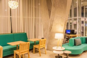 Un intérieur moderne avec un canapé vert, des chaises en bois, une table et une lampe.