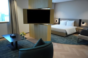 Una habitación de hotel moderna con cama, televisor, escritorio y silla.