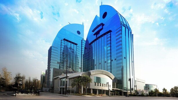 A modern hotel with a distinctive curved facade and a prominent logo.