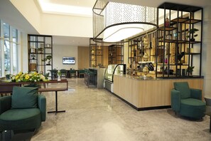 Un moderno vestíbulo de hotel con mostrador de recepción, zona de estar y estanterías decorativas.