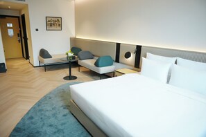 A hotel room with a bed, a sofa, a table, and a chair.