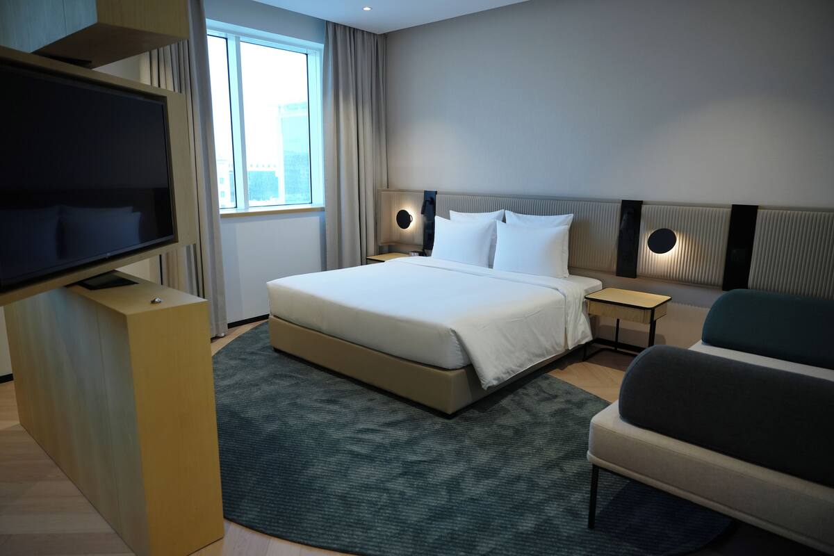 Une chambre d’hôtel moderne dotée d’un grand lit, de tables de chevet, d’une télévision et d’un coin salon.