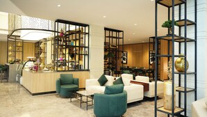 A modern hotel lobby with a reception desk, seating area, and decorative shelves.