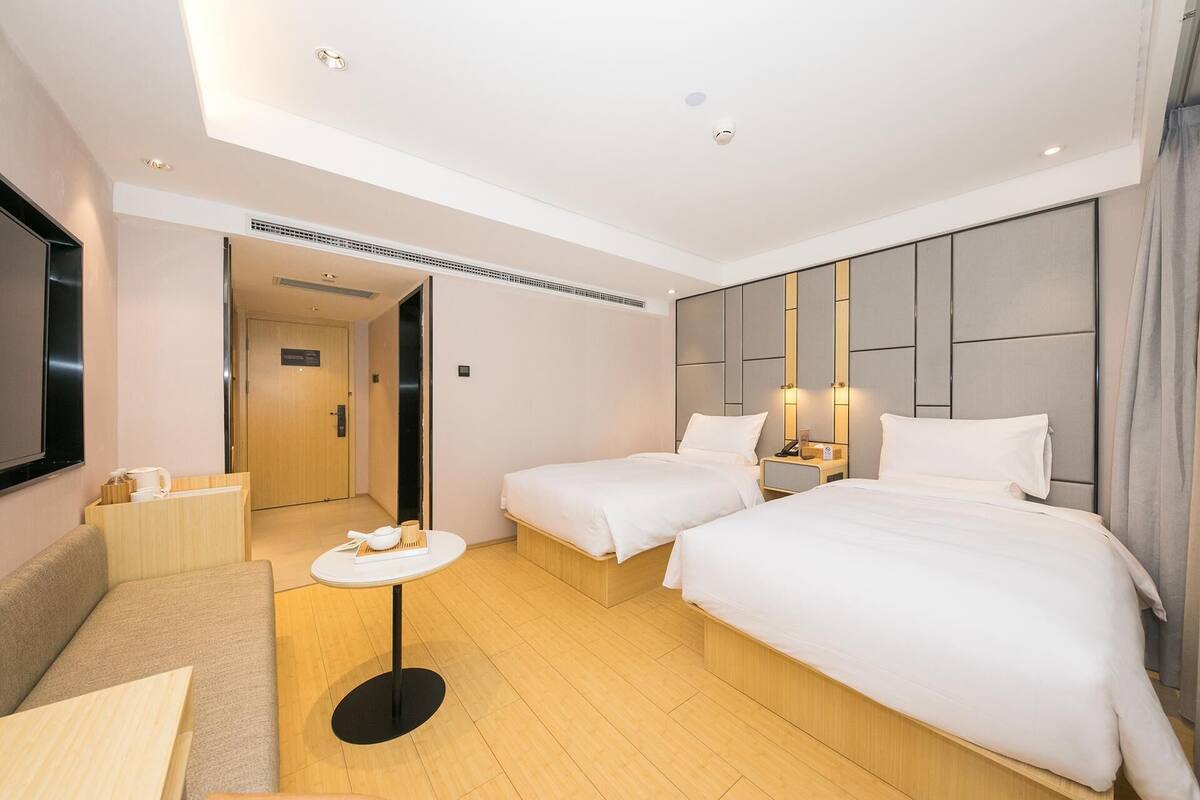 Une chambre d’hôtel avec deux lits, une petite table, un canapé et un téléviseur.