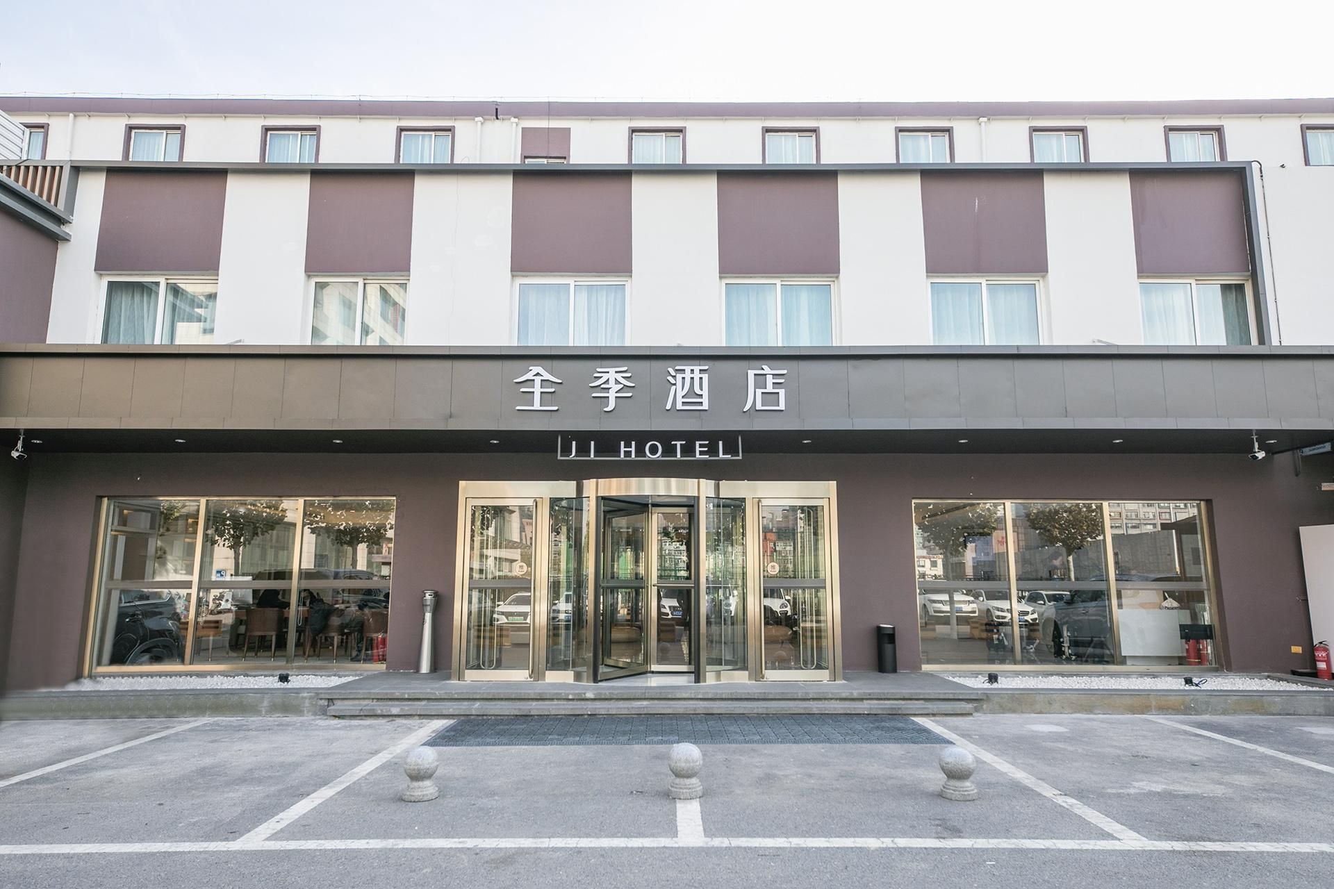 A hotel with a modern facade, large glass entrance, and a sign reading 'JI HOTEL'.