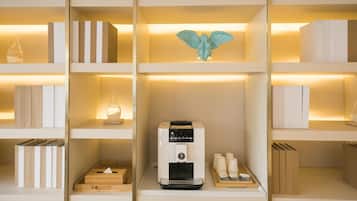 A neatly organized shelf with books, a decorative angel, a coffee machine, and a tray with cups.