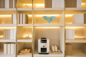 A neatly organized shelf with books, a decorative angel, a coffee machine, and a tray with cups. - Ji Hotel Beijing Guomao (Beijing)
