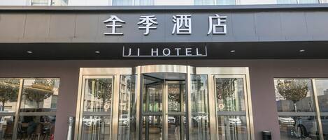A hotel entrance with a revolving door and glass doors.
