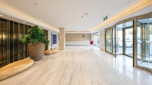 A spacious lobby with a large reception desk, a potted plant, and a glass entrance. - Ji Hotel Beijing Guomao (Beijing)