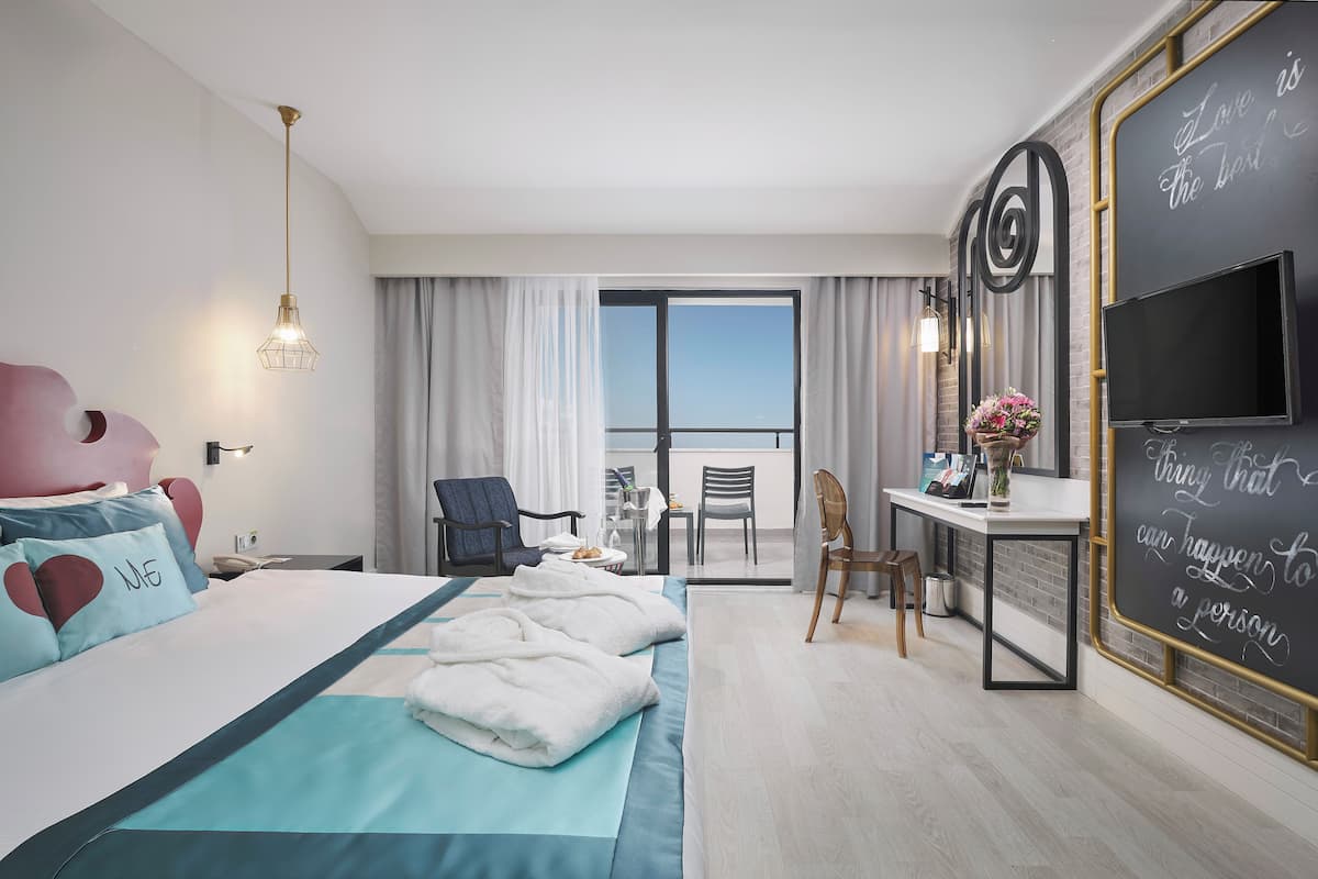 Ein Hotelzimmer mit Bett, Schreibtisch, Stuhl, Fernseher und einem Balkon mit Aussicht.