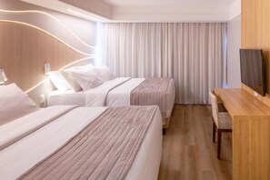 A hotel room with two beds, a wooden desk, a television, and a large window with curtains. - Rio Quente Resorts Refugio Grand Premium (Rio Quente)
