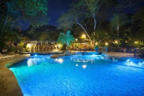 A nighttime swimming pool with a wooden deck and lounge chairs. - Rio Quente Resorts Refugio Grand Premium (Rio Quente)