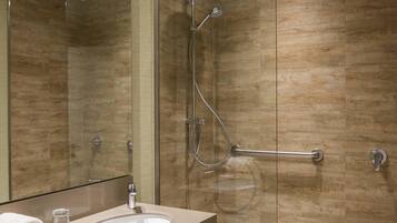 Un baño moderno con cabina de ducha de vidrio, tocador con lavabo y espejo.